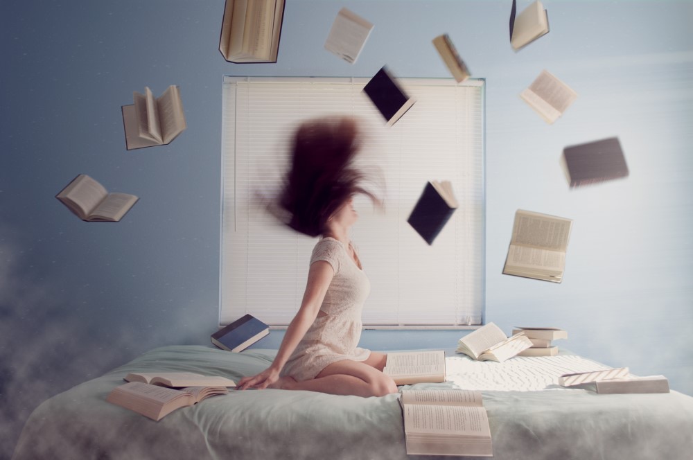 Woman sitting on bed with flying books and exam stress tips